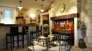 A rustic interior with stone walls, a fireplace, and a bar area with chairs and a table. - Le Mas des Bories - Grand Périgueux (Antonne-et-Trigonant)