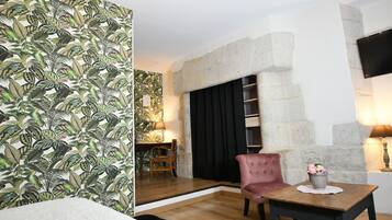 A room with a stone fireplace, a wooden table with a vase of flowers, and a patterned wallpaper.