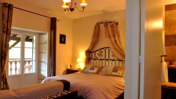 Un dormitorio con cama, mesita de noche con lámpara, ventana con cortinas y candelabro.