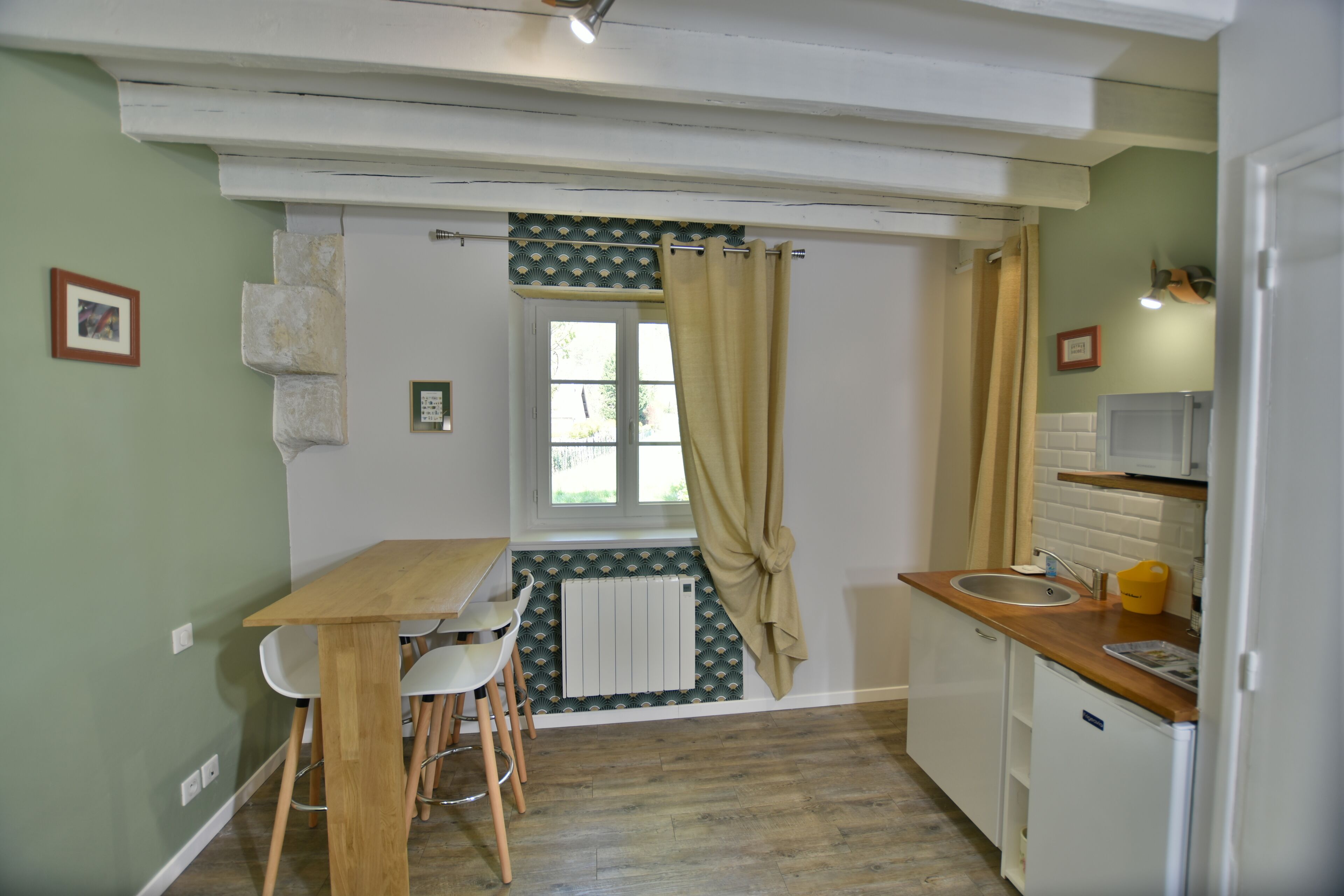 A compact kitchen with a wooden table and chairs, a sink, and a refrigerator.