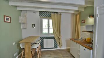 A compact kitchen with a wooden table and chairs, a sink, and a refrigerator.