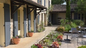 A courtyard with a stone pathway, potted plants, and outdoor seating. - Le Mas des Bories - Grand Périgueux (Antonne-et-Trigonant)