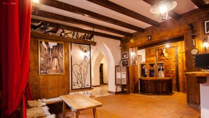 A rustic interior with wooden beams, a wooden bar area, and a red curtain. - Hotel Mille Pini (Scanno)