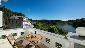 A balcony with a table, chairs, and a scenic view of a lake and forest. - Sam Tuyen Lam Resort (Xuan Huong - Da Lat)