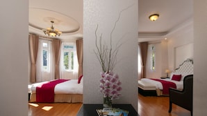 A hotel room with two beds, a chandelier, a vase with flowers, and a table with a magazine. - Sam Tuyen Lam Resort (Xuan Huong - Da Lat)