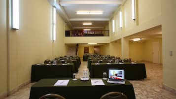 Une salle de conférence équipée de plusieurs tables, de chaises et d’un ordinateur portable posé sur l’une des tables.