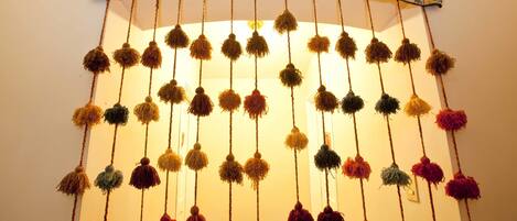A wall with a decorative hanging featuring multiple colorful pom-poms.