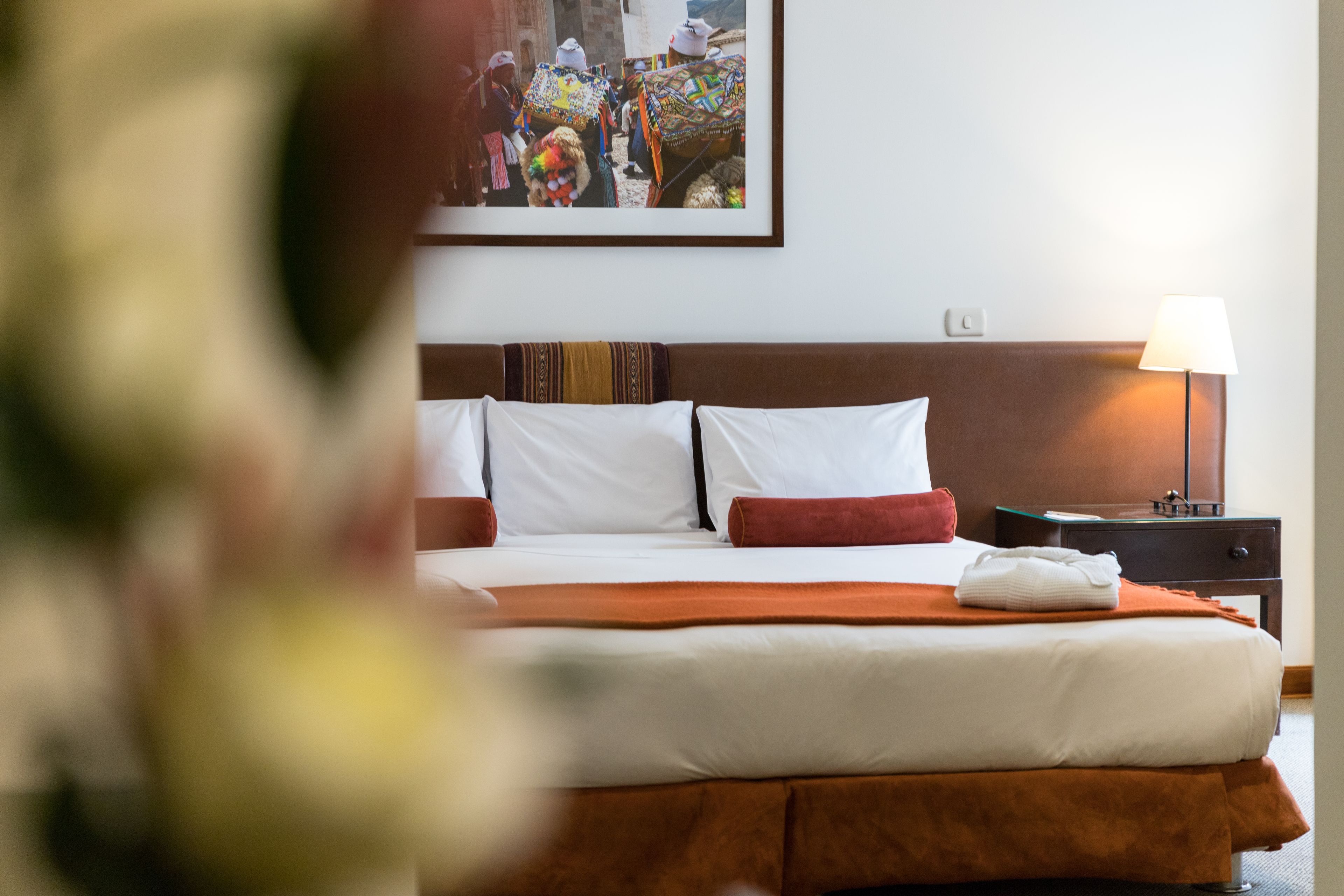 Une chambre d’hôtel avec un grand lit, une table de chevet, une lampe et un tableau encadré au mur.
