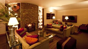 A cozy living room with a fireplace, comfortable seating, and a flat-screen TV. - LP Los Portales Hotel Cusco (Cusco)