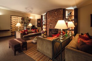 A cozy living room with a brick wall, a sofa, a coffee table, and a bookshelf.