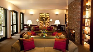 A cozy living room with a sofa, two lamps, a fireplace, and a bookshelf. - LP Los Portales Hotel Cusco (Cusco)