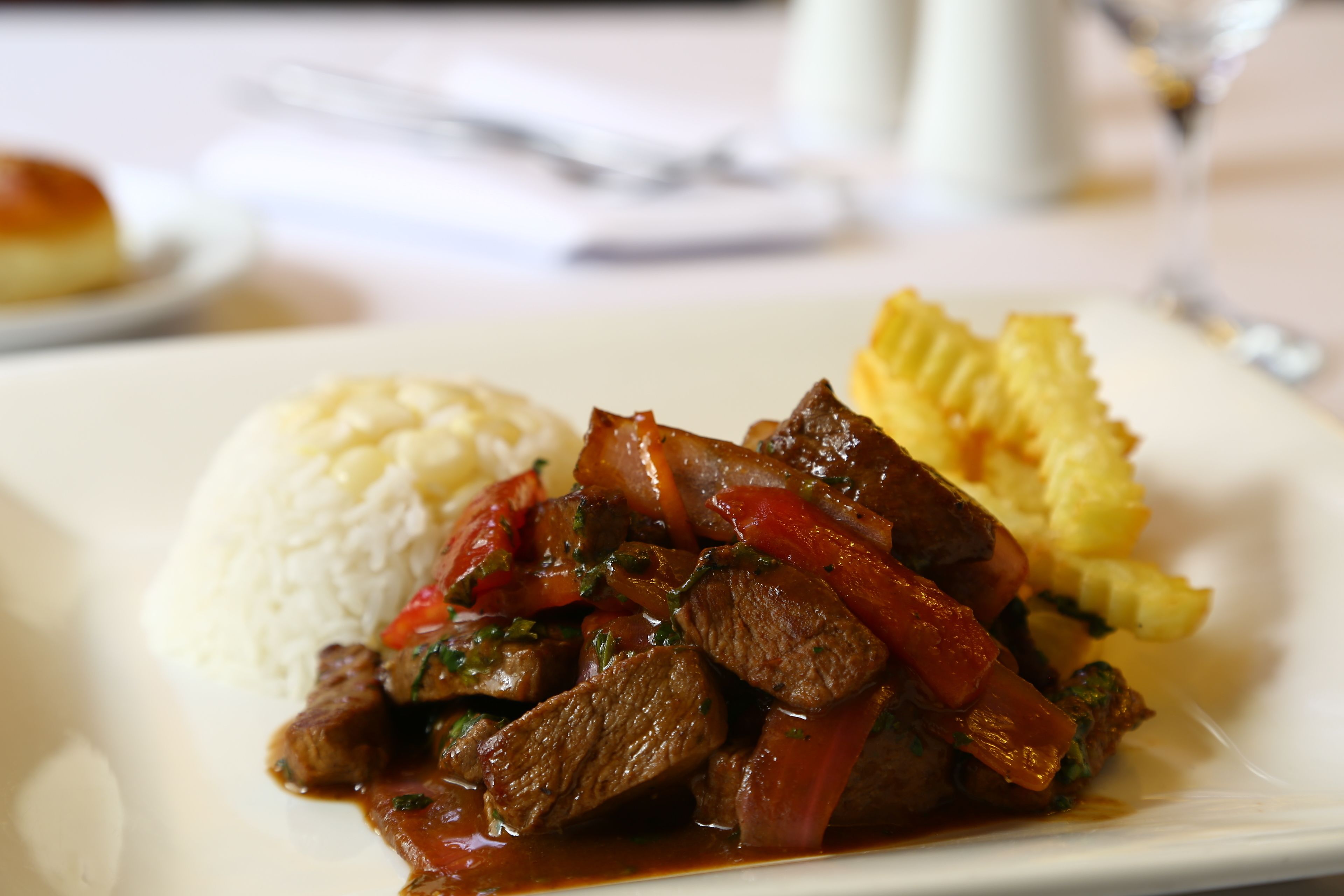 Un plato de guiso de carne con verduras, acompañamiento de arroz blanco y una tajada de plátano frito.