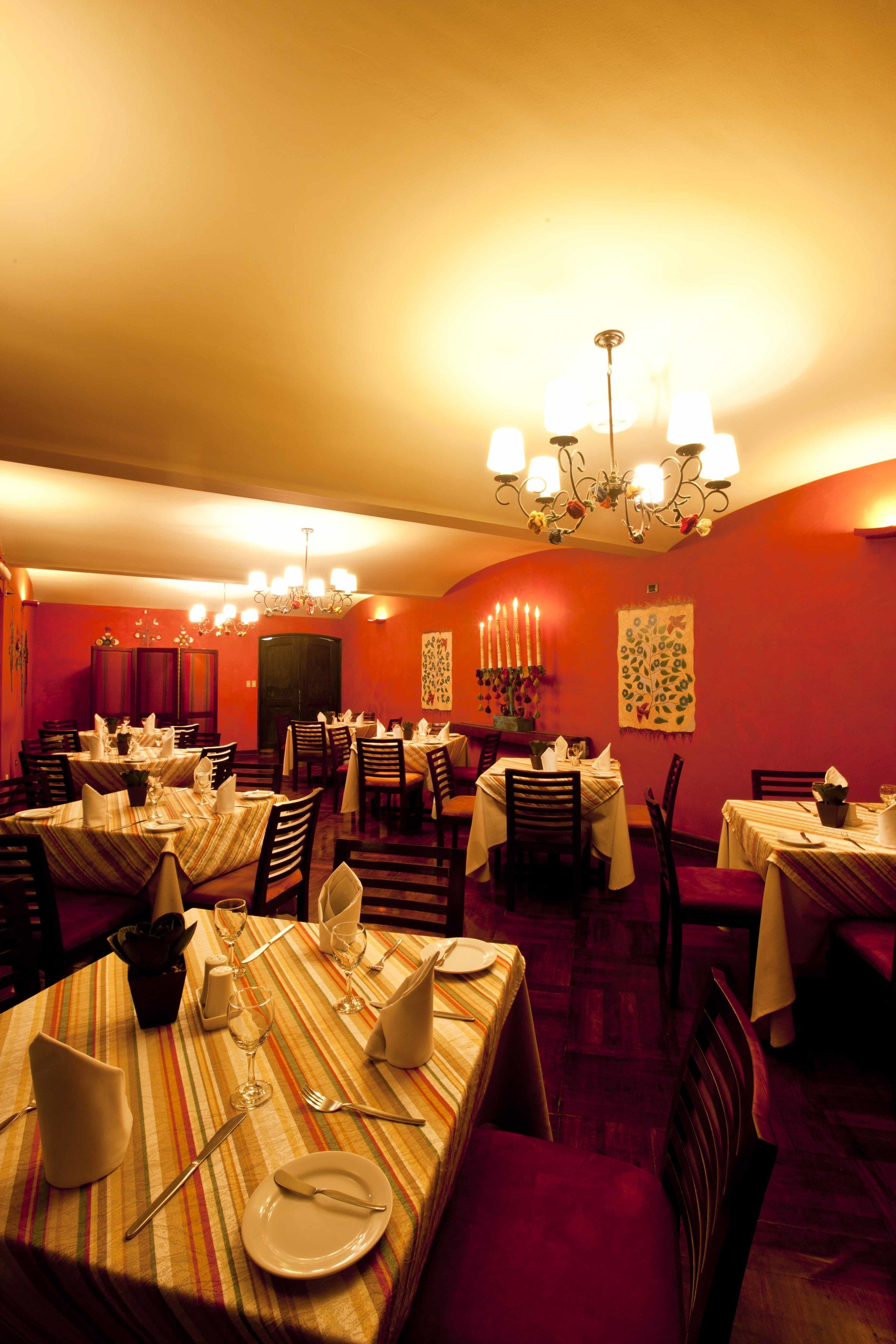 A restaurant with multiple tables set for dining, featuring striped tablecloths and candlelit ambiance.