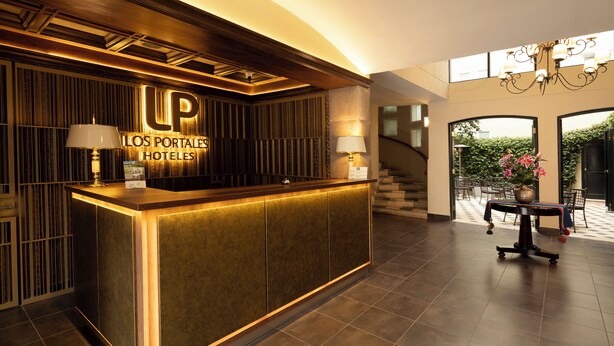 A reception desk with a sign reading "Los Portales Hotels" and a staircase leading to an outdoor area. - LP Los Portales Hotel Cusco (Cusco)