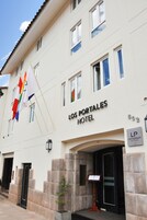 Entrada de hotel con un cartel que dice 'Los Portales Hotel' y una exhibición de banderas.