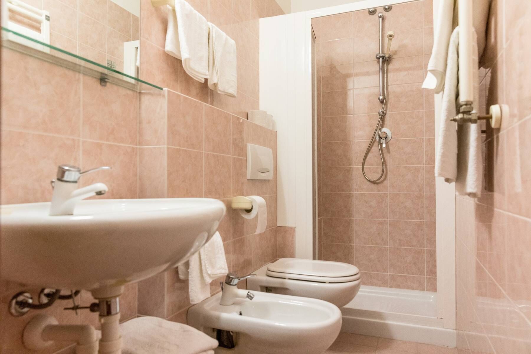 A bathroom with a sink, toilet, bidet, and shower.