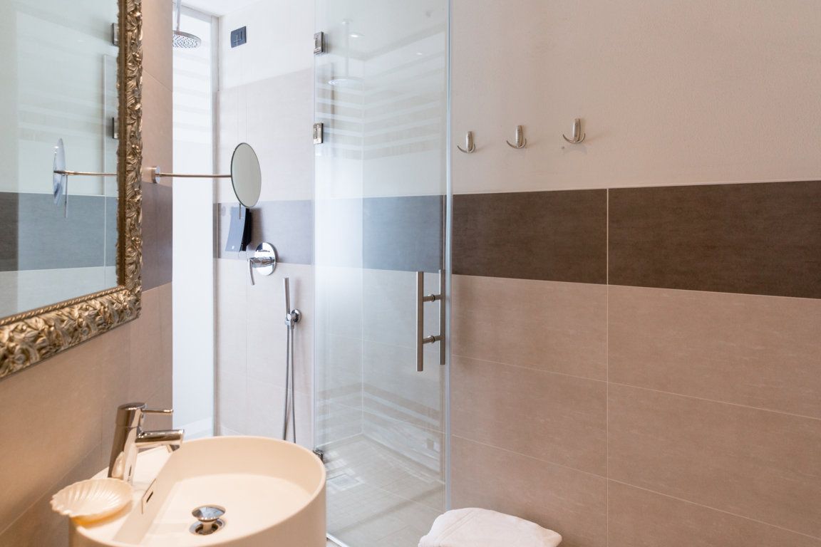 Un baño con cabina de ducha de vidrio, un lavamanos con espejo y un inodoro.