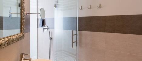 Un baño con cabina de ducha de vidrio, un lavamanos con espejo y un inodoro.