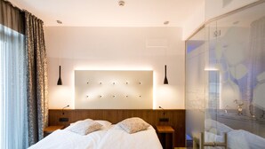 A modern hotel room with a large bed, two bedside tables, a headboard with integrated lighting, and a glass partition with a map. - Hotel Pace (Torri del Benaco)