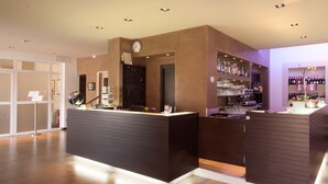 A modern bar area with wooden counters, a clock, and shelves of bottles and glasses. - Hotel Pace (Torri del Benaco)