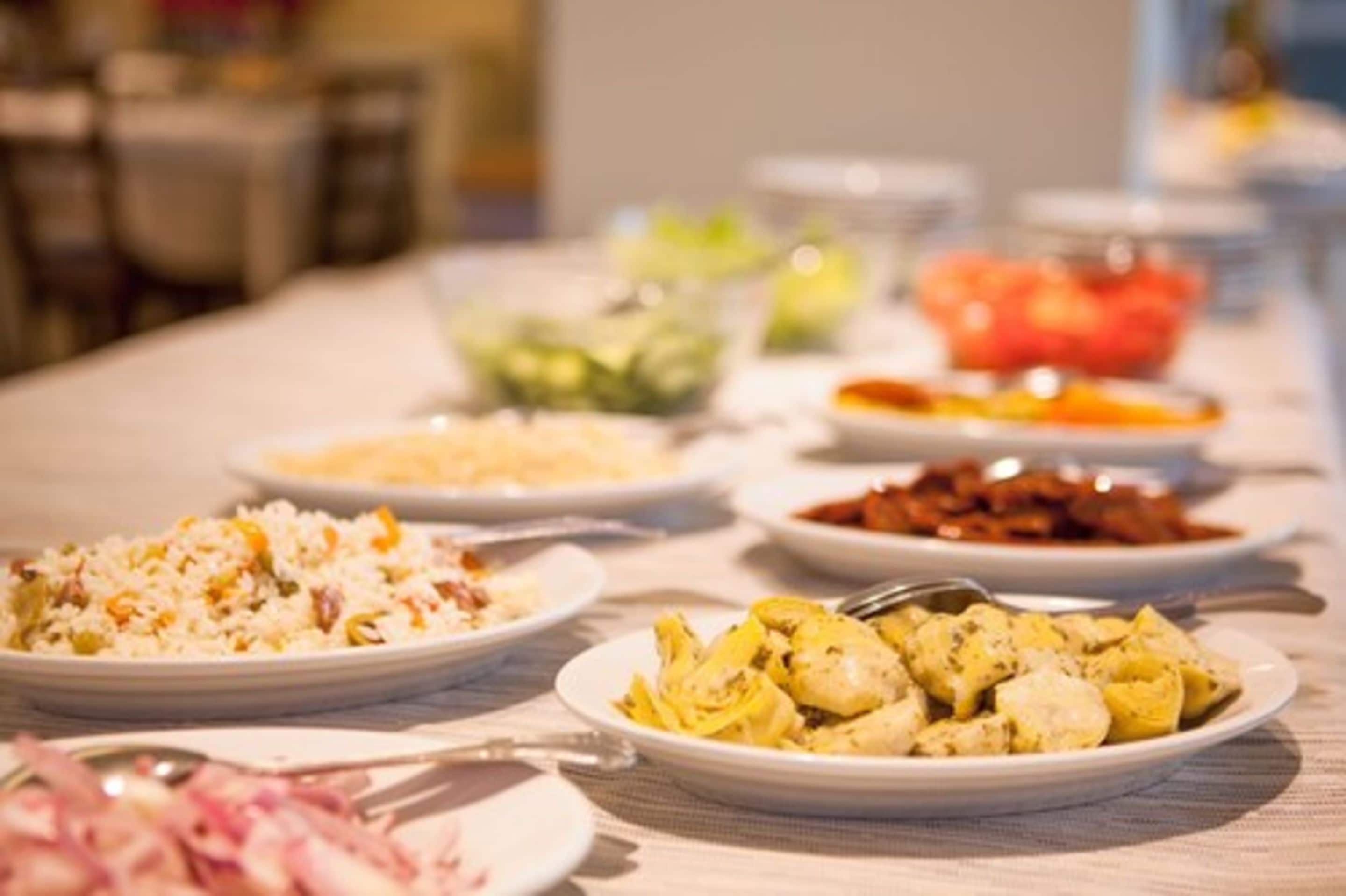 A buffet table with various dishes including rice, chicken, and vegetables.