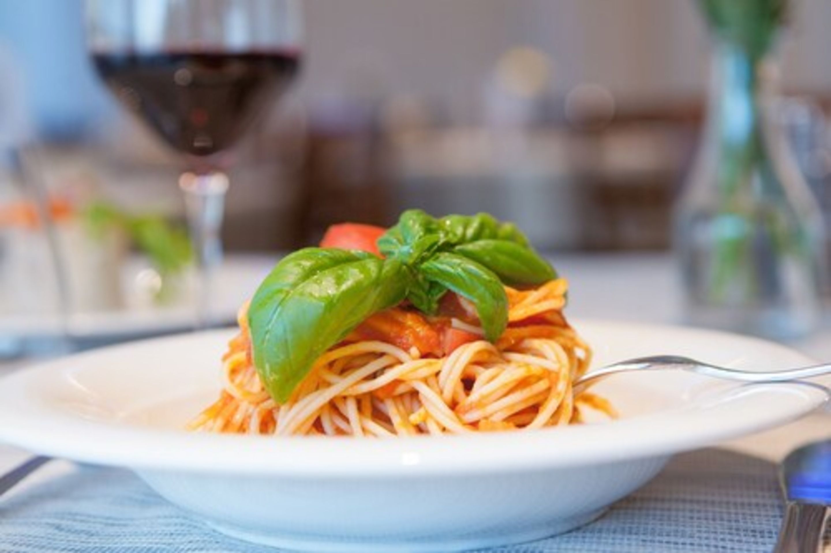 Une assiette de spaghettis garnie d’une feuille de basilic.