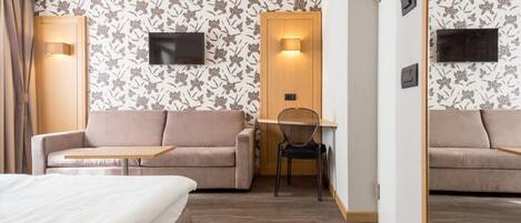 A hotel room with a bed, a sofa, a desk, and a chair.