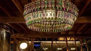 A room with a unique chandelier made of bottles, wooden beams, and a bench area. - Sleepbox Chiangmai Hotel (Chiang Mai)