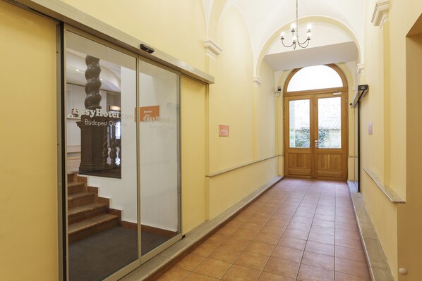 A hotel corridor with a glass door, a staircase, and a wooden door at the end. - easyHotel Budapest Oktogon (Budapest)
