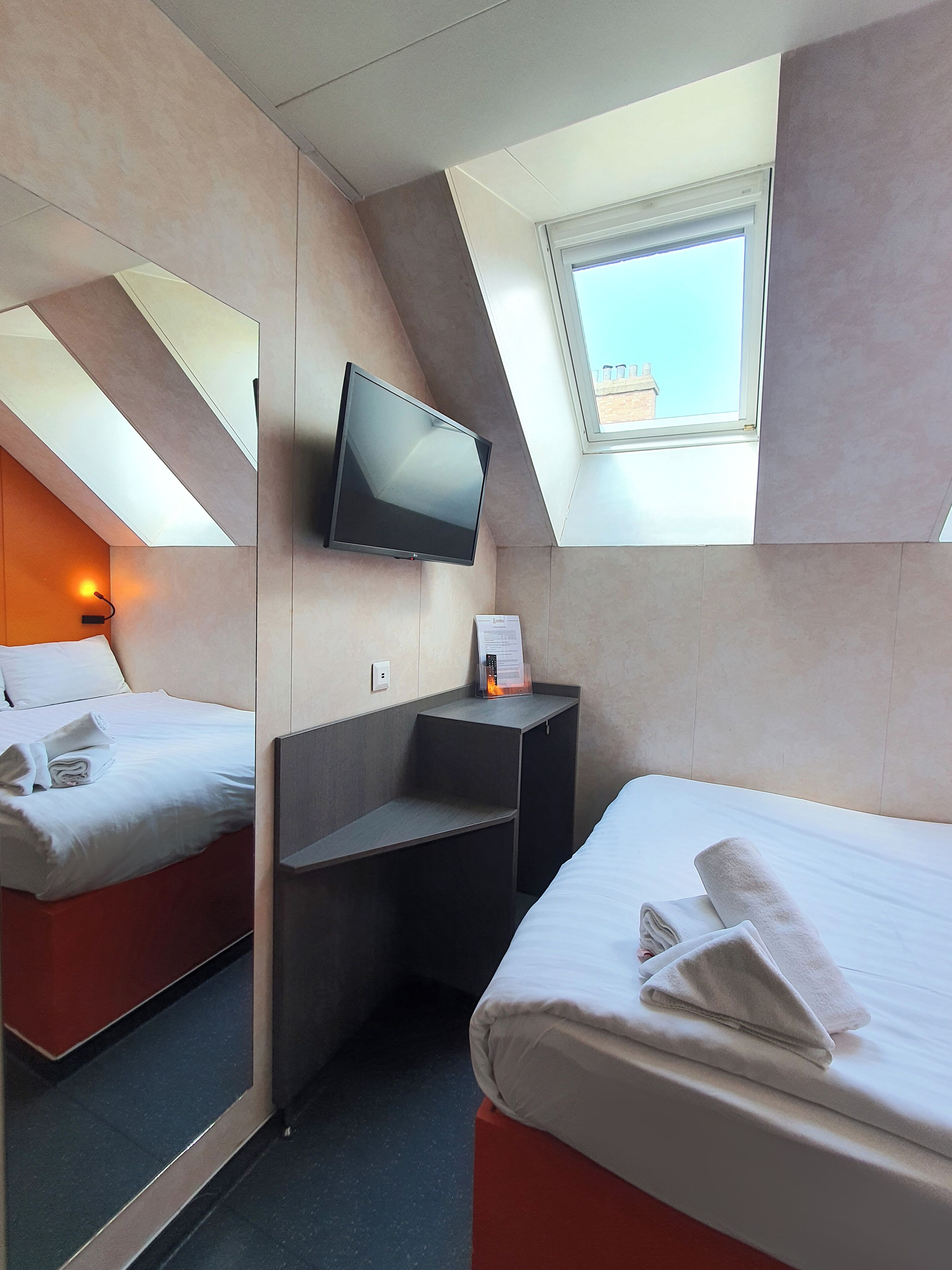 Ein Hotelzimmer mit Bett, Wandfernseher, kleinem Schreibtisch und einem Fenster mit Blick.