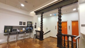 Un vestíbulo con estación de café, escalera y área de recepción.