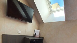 A hotel room with a bed, a flat-screen TV mounted on the wall, a small desk, and a window providing a view of the sky. - TL Hotel Budapest (Budapest)