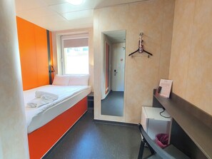 A hotel room with a bed, a window, a mirror, and a small desk with a chair. - TL Hotel Budapest (Budapest)