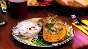A plate with a sandwich and a bowl of dip on a table.