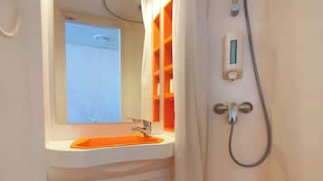 Un baño con lavamanos, espejo, ducha y perchero.
