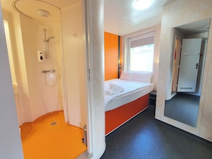 A compact hotel room with a shower, a bed, and a window. - TL Hotel Budapest (Budapest)