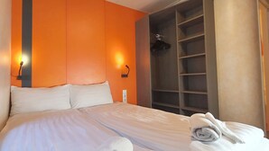 Una habitación de hotel con cama, armario y un calentador de pared.