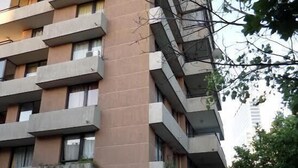 Een meerhoog gebouw met balkons, een zichtbare winkelpui en een heldere lucht.