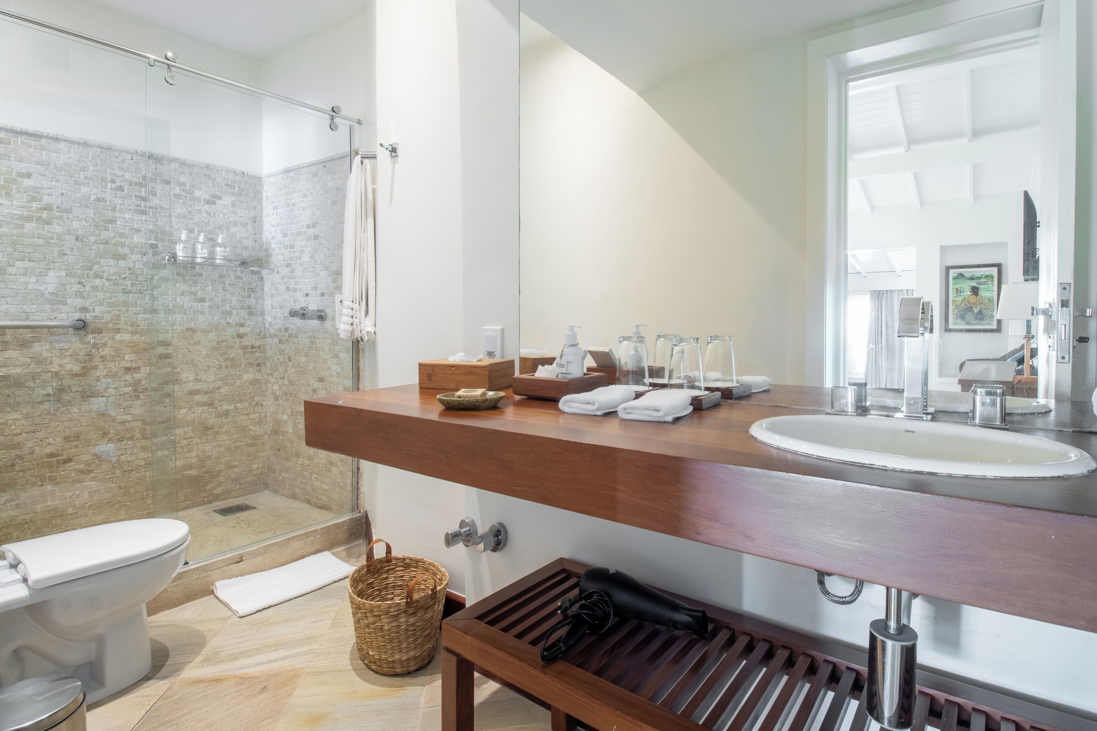 A modern bathroom with a glass shower enclosure, a wooden vanity with a sink, and a toilet.