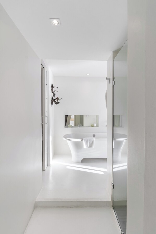 A modern bathroom with a freestanding bathtub, a mirror, and a decorative wall piece.