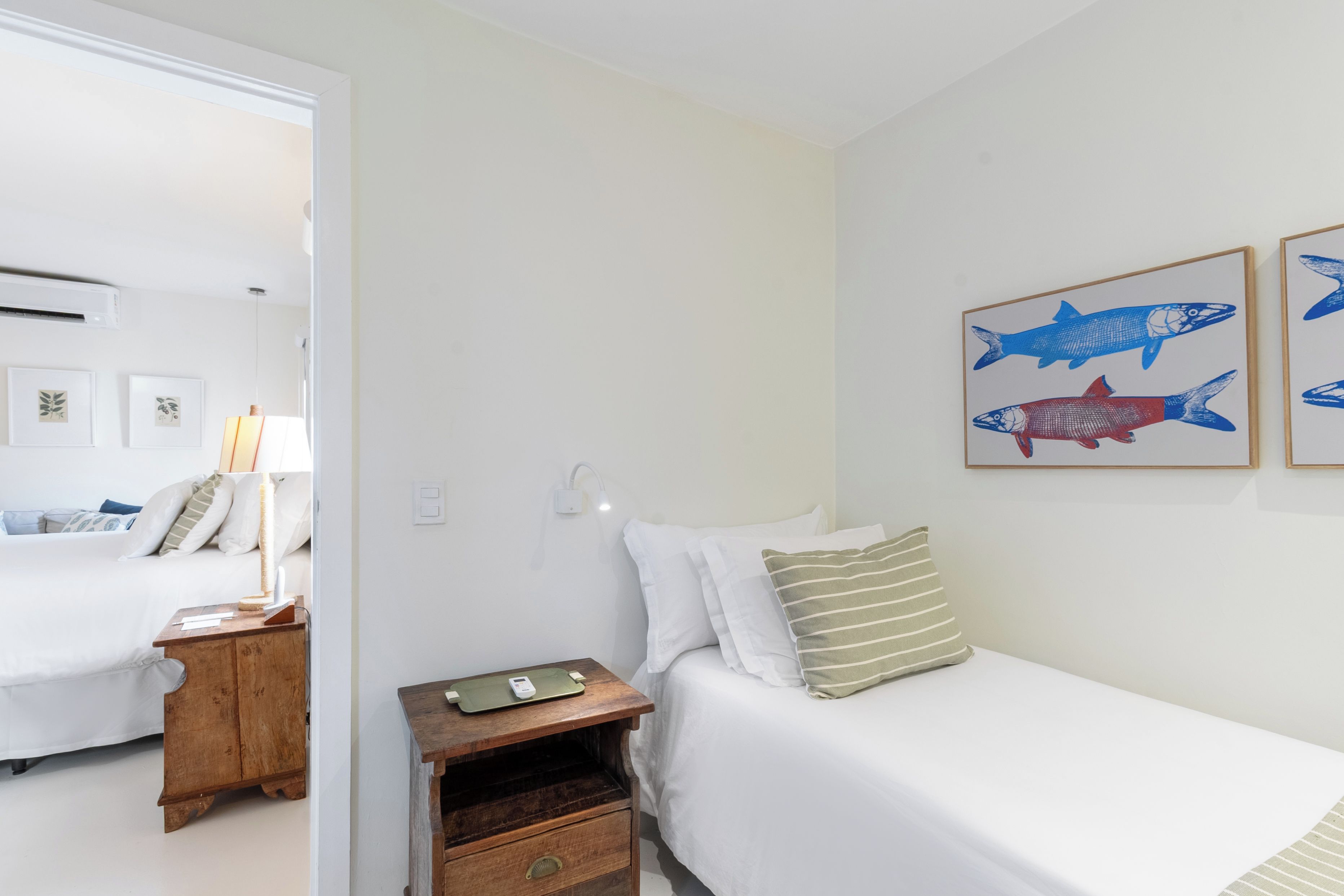 A bedroom with a bed, bedside table, lamp, and wall art.