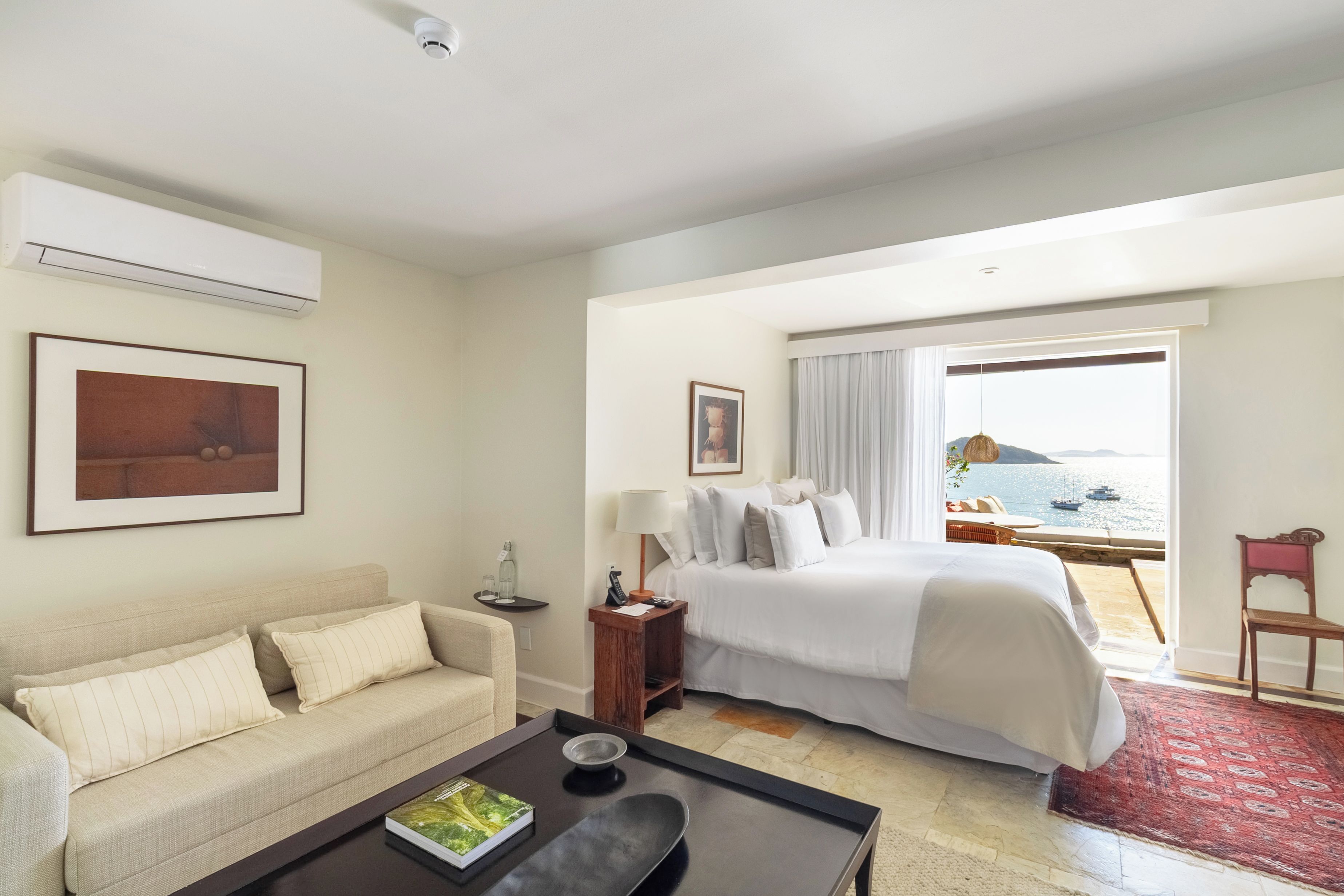 Habitación de hotel con cama, sofá, una mesa de centro y vista al mar.