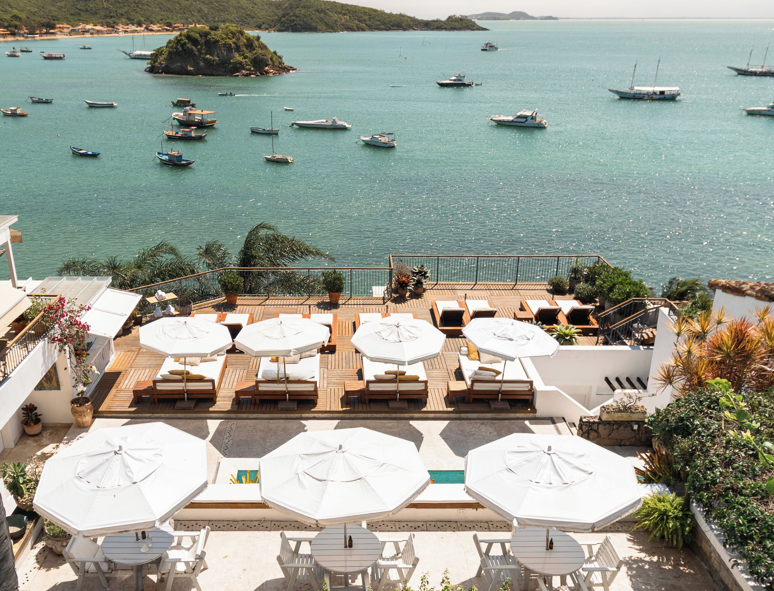 A terrace with outdoor seating and umbrellas overlooking a marina with boats.