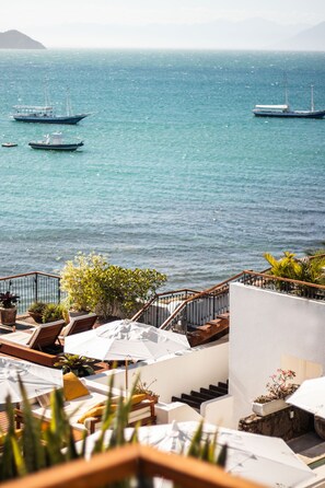 A coastal hotel with outdoor seating overlooking the sea, featuring a staircase and potted plants. - Casas Brancas Boutique Hotel & Spa (Búzios)