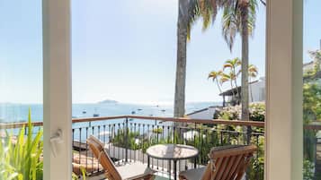 A balcony with a view of the sea, featuring a table and two chairs.