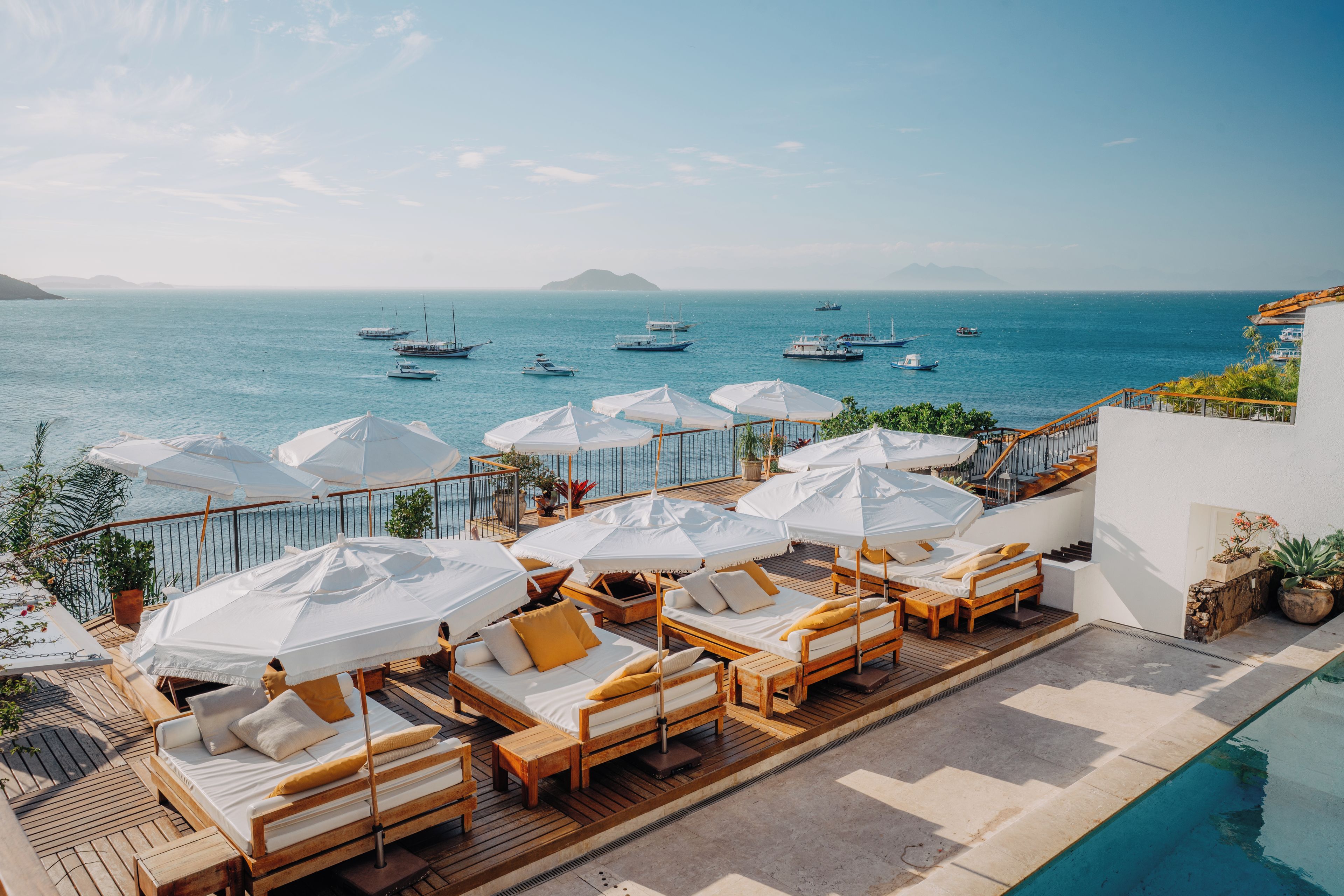 A deck with sun loungers and umbrellas overlooking a marina with boats.