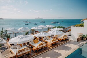 A deck with sun loungers and umbrellas overlooking a marina with boats.
