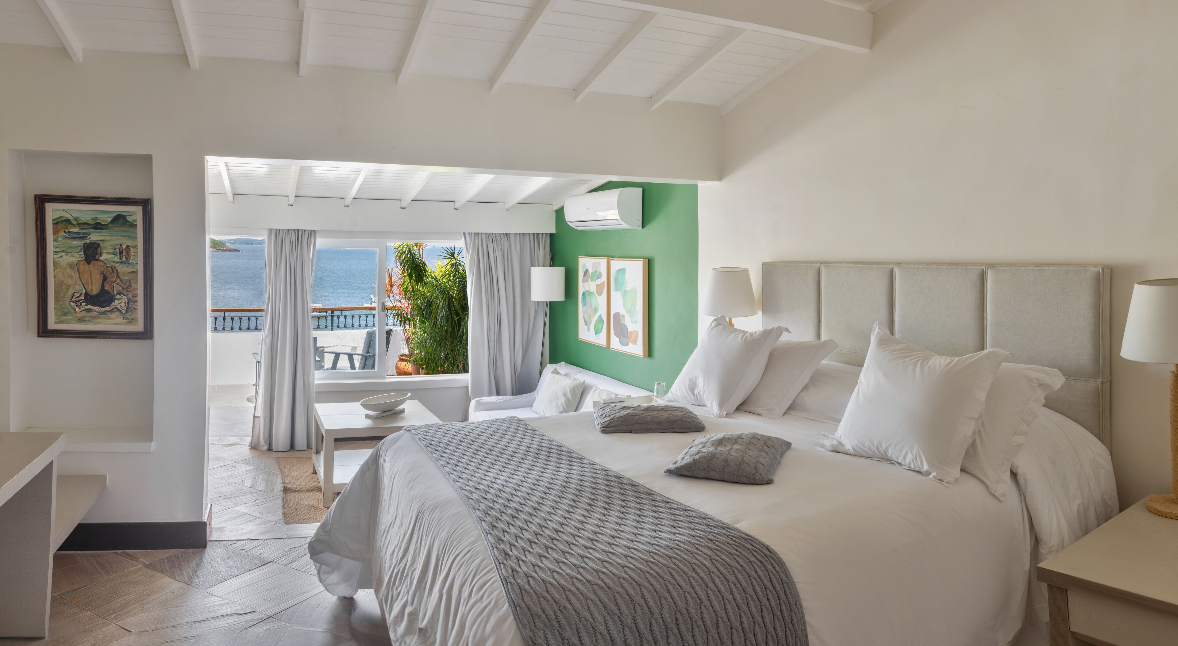 Quarto de hotel com uma cama grande, uma mesa de trabalho e vista para o mar.
