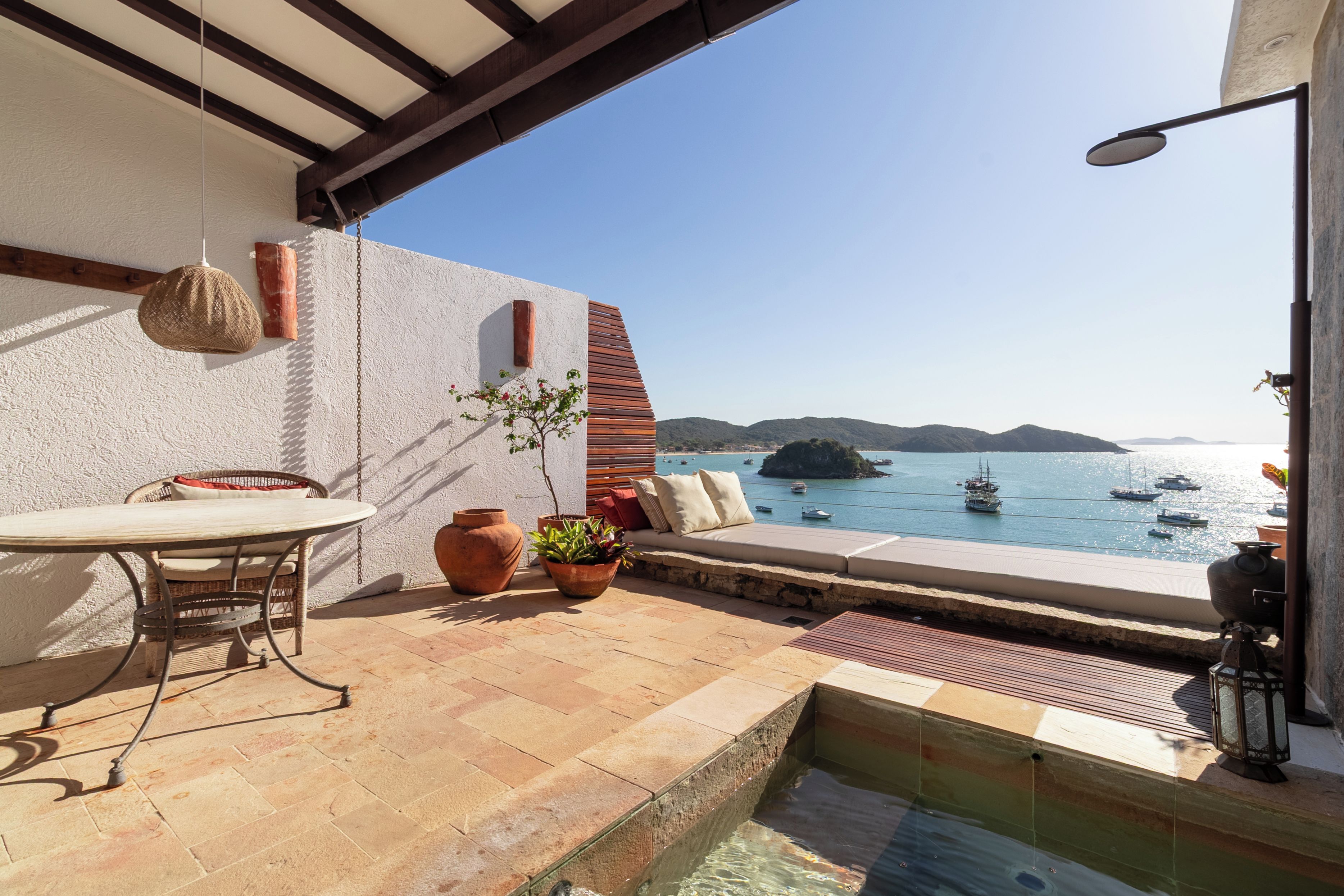 Una terraza con una mesa y sillas, una piscina pequeña y vistas al mar con barcos.