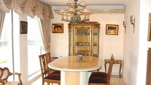 A dining room with a round table, four chairs, a chandelier, and a cabinet with glass doors.